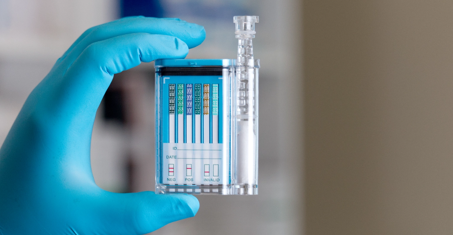 Gloved hands holding EZ Saliva I for workplace rapid screening